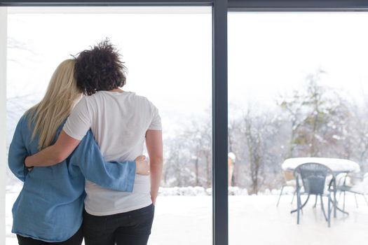 romantic happy young couple enjoying morning coffee by the window on cold winter day at home