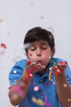 Happy kid celebrating party with blowing confetti