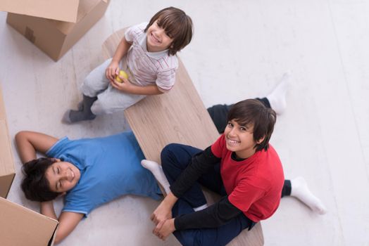 portrait of happy young boys with cardboard boxes around them in a new modern home top view