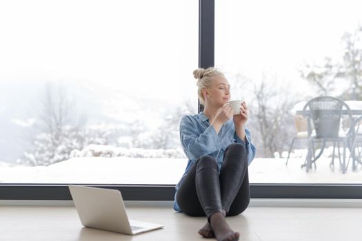 Real Woman Using laptop on the floor Drinking Coffee Enjoying Relaxing at cold winter day