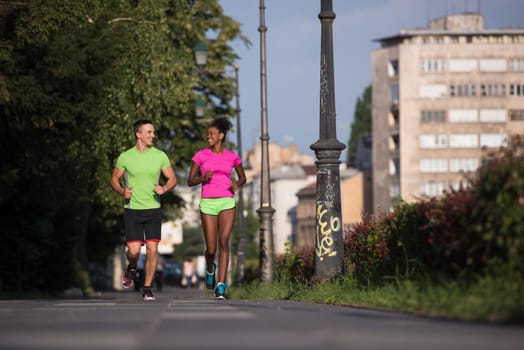 healthy young multiethnic couple jogging in the city on a sunny summer day