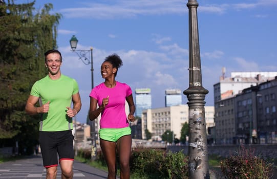 healthy young multiethnic couple jogging in the city on a sunny summer day