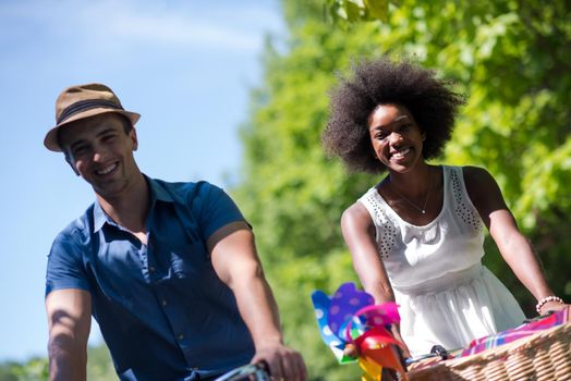 a young man and a beautiful African American girl enjoying a bike ride in nature on a sunny summer day