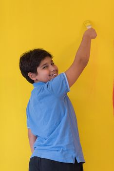 Portrait of a young boy painter with a brush in his hand in front of colored background