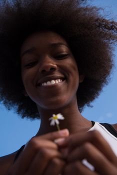 portrait of a young beautiful African American girl with a flower of daisy in her hand