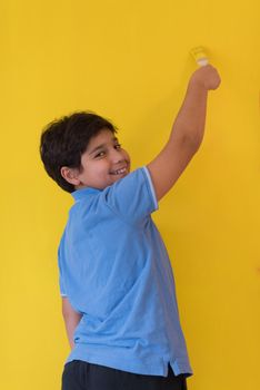 Portrait of a young boy painter with a brush in his hand in front of colored background