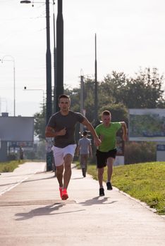 athletic young men enjoy running while the sun rises over the city