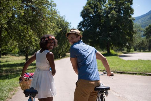 a young man and a beautiful African American girl enjoying a bike ride in nature on a sunny summer day