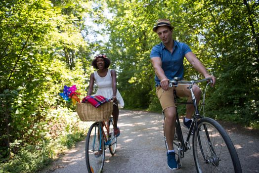 a young man and a beautiful African American girl enjoying a bike ride in nature on a sunny summer day