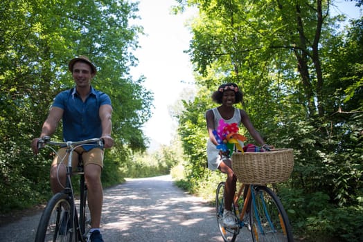 a young man and a beautiful African American girl enjoying a bike ride in nature on a sunny summer day