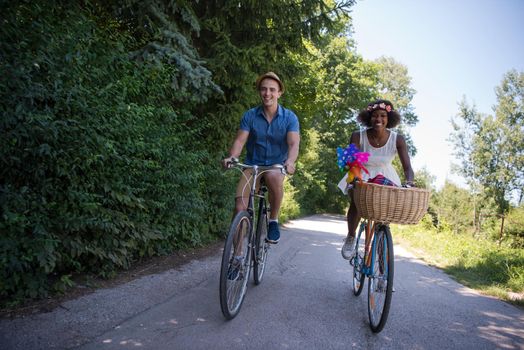 a young man and a beautiful African American girl enjoying a bike ride in nature on a sunny summer day