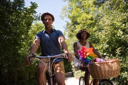 a young man and a beautiful African American girl enjoying a bike ride in nature on a sunny summer day