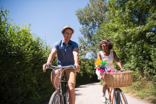 a young man and a beautiful African American girl enjoying a bike ride in nature on a sunny summer day