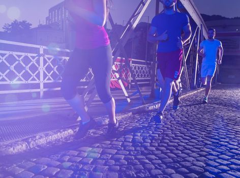 urban sports, group of young healthy people jogging across the bridge in the city at early morning in night