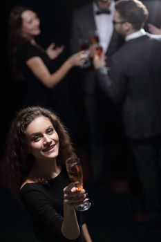 stylish young woman with glass of champagne on the background of friends