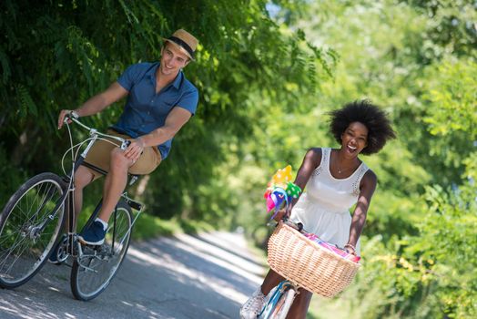 a young man and a beautiful African American girl enjoying a bike ride in nature on a sunny summer day