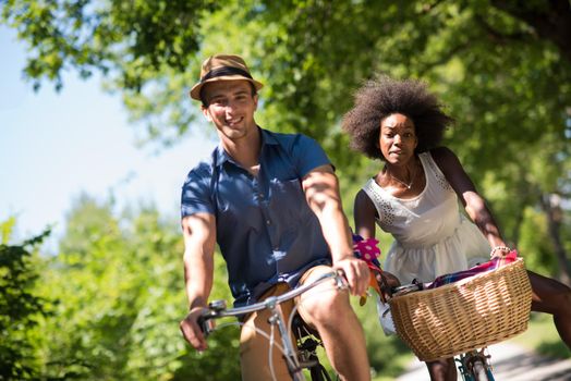 a young man and a beautiful African American girl enjoying a bike ride in nature on a sunny summer day