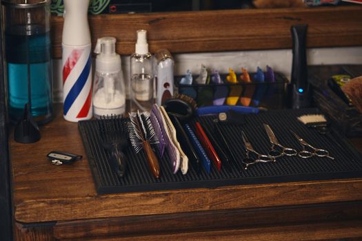 Close-up view of set of professional barber tools on wooden shelf in barbershop indoor