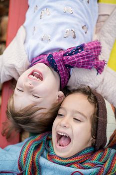 cutte little girl and boy in childrens park having fun and joy while playing in playground on autumn cloudy day