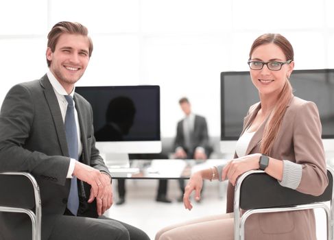 businessman and business woman sitting at office Desk and looking at camera.