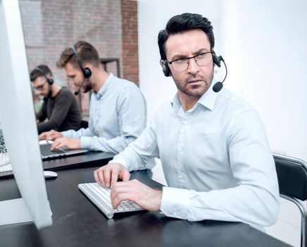 serious businessman in a headset sitting at a Desk in a call center