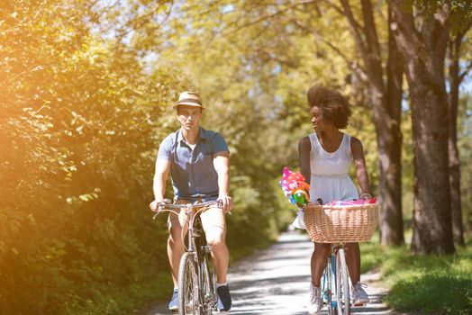 a young man and a beautiful African American girl enjoying a bike ride in nature on a sunny summer day