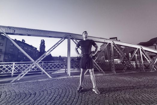 urban sports, young healthy man jogging across the bridge in the city at early morning in night