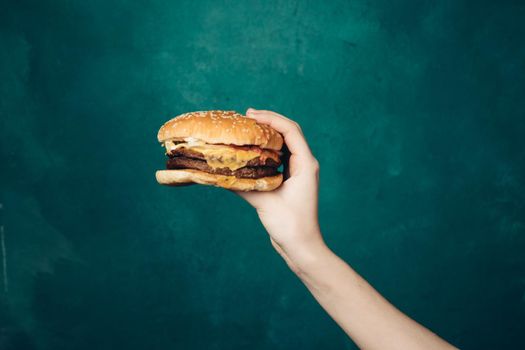 hamburger in hands close-up fast food green background. High quality photo