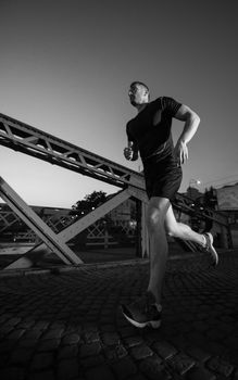 urban sports, young healthy man jogging across the bridge in the city at early morning in night