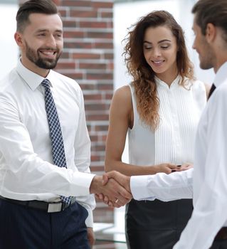 handshake business partners and business team standing in office.