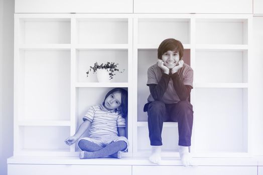 happy young boys are having fun while posing on a shelf in a new modern home