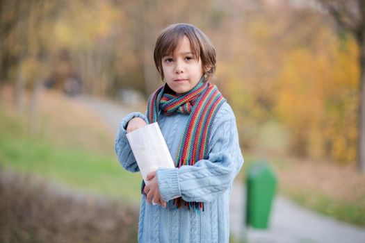 cute little boy in park eating popcorn in autumn cloudy day