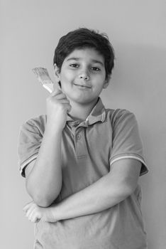 Portrait of a young boy painter with a brush in his hand in front of colored background