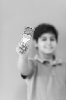 Portrait of a young boy painter with a brush in his hand in front of colored background