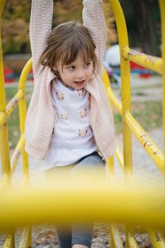 cute little girl portrait while  having fun in playground park on cludy autum day
