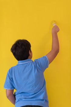 Portrait of a young boy painter with a brush in his hand in front of colored background