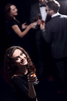 stylish young woman with glass of champagne on the background of friends