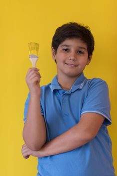 Portrait of a young boy painter with a brush in his hand in front of colored background