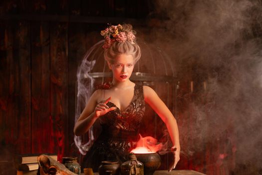Halloween Witch with cauldron. Beautiful young woman conjuring, making witchcraft. Standing spooky dark magic dungeon dark room. Enchantress prepare love potion use magiс spell