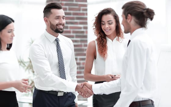 handshake business partners and business team standing in office.