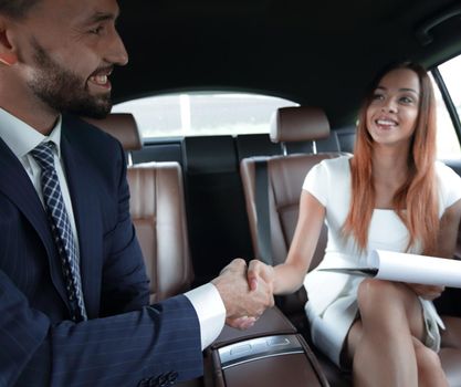 Business handshake to close the success agreement in back seat car