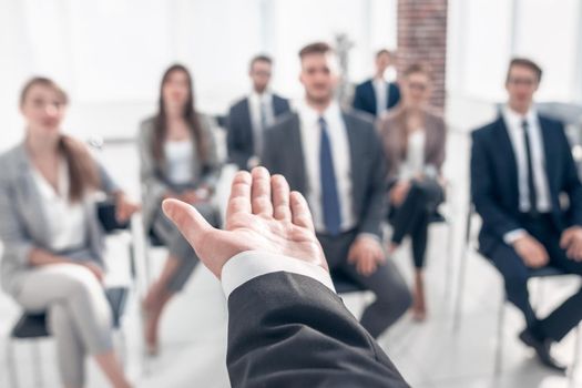 rear view.Business coach gesturing his hand in front of a group of people.close up.