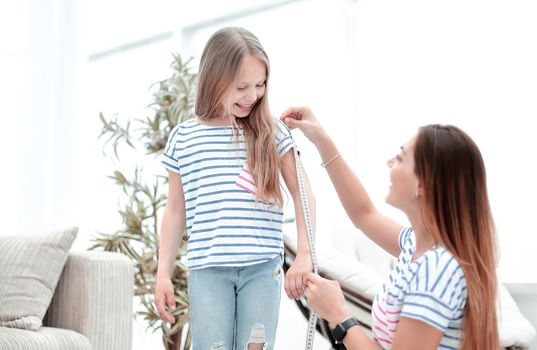 attentive mother and daughter make measurements for new clothes .the concept of parenting
