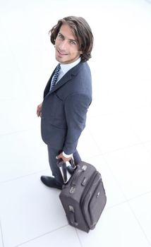 side view.smiling businesswoman with travel suitcase looking at the camera .photo with copy space