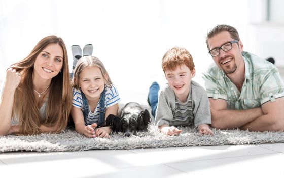 parents with children lying in the living room on the carpet.photo with copy space