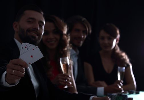 Elegant young smiling people are drinking wine at the poker table