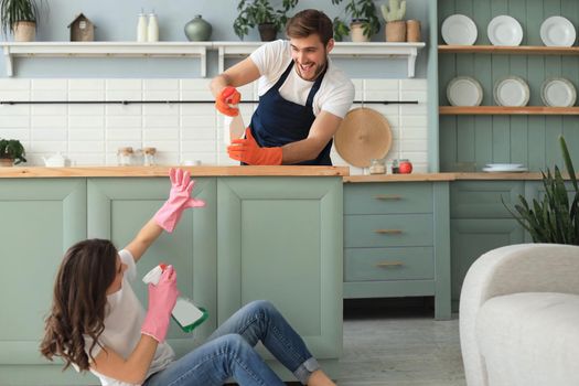 Young happy couple is having fun while doing cleaning at home
