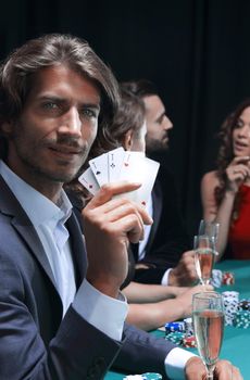 Poker players in casino with cards and chips on black background