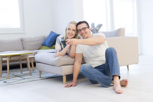 Young couple on the sofa watching television together in their luxury home