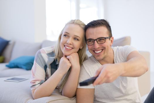 Young couple on the sofa watching television together in their luxury home